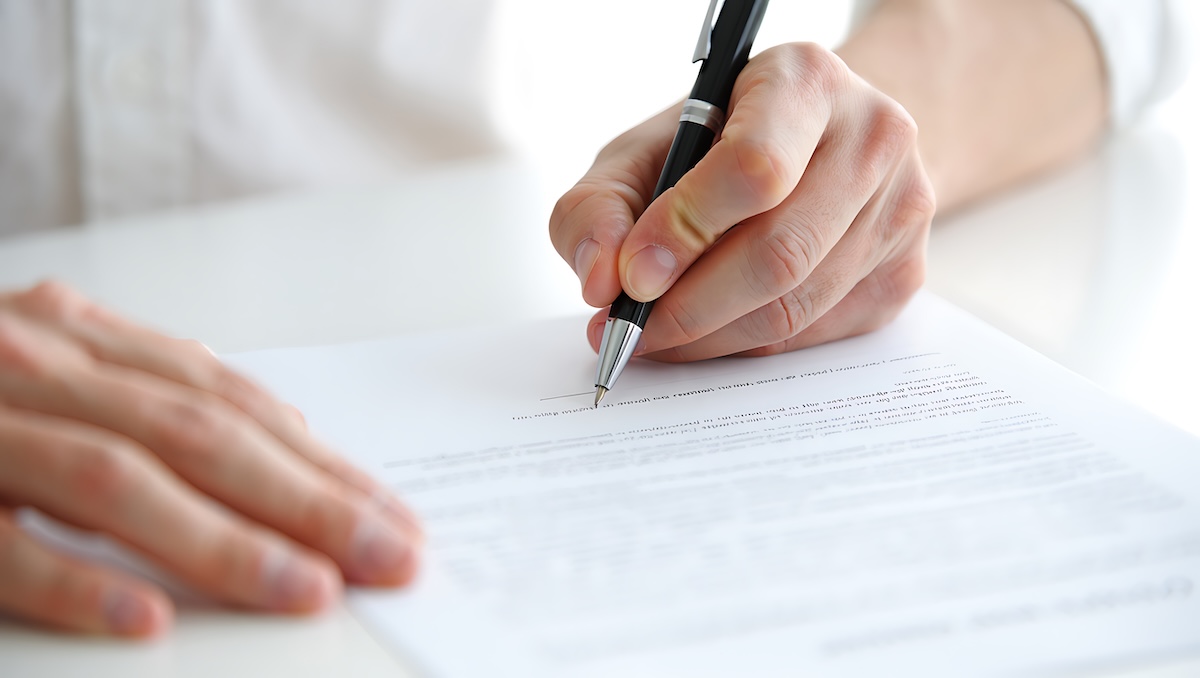 Businessman filling out paperwork and signing legal form at office desk with document business paperwork contract